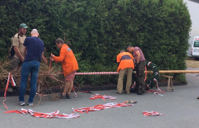 Der Maibaum wird mit Bändern und einem Kranz geschmückt.